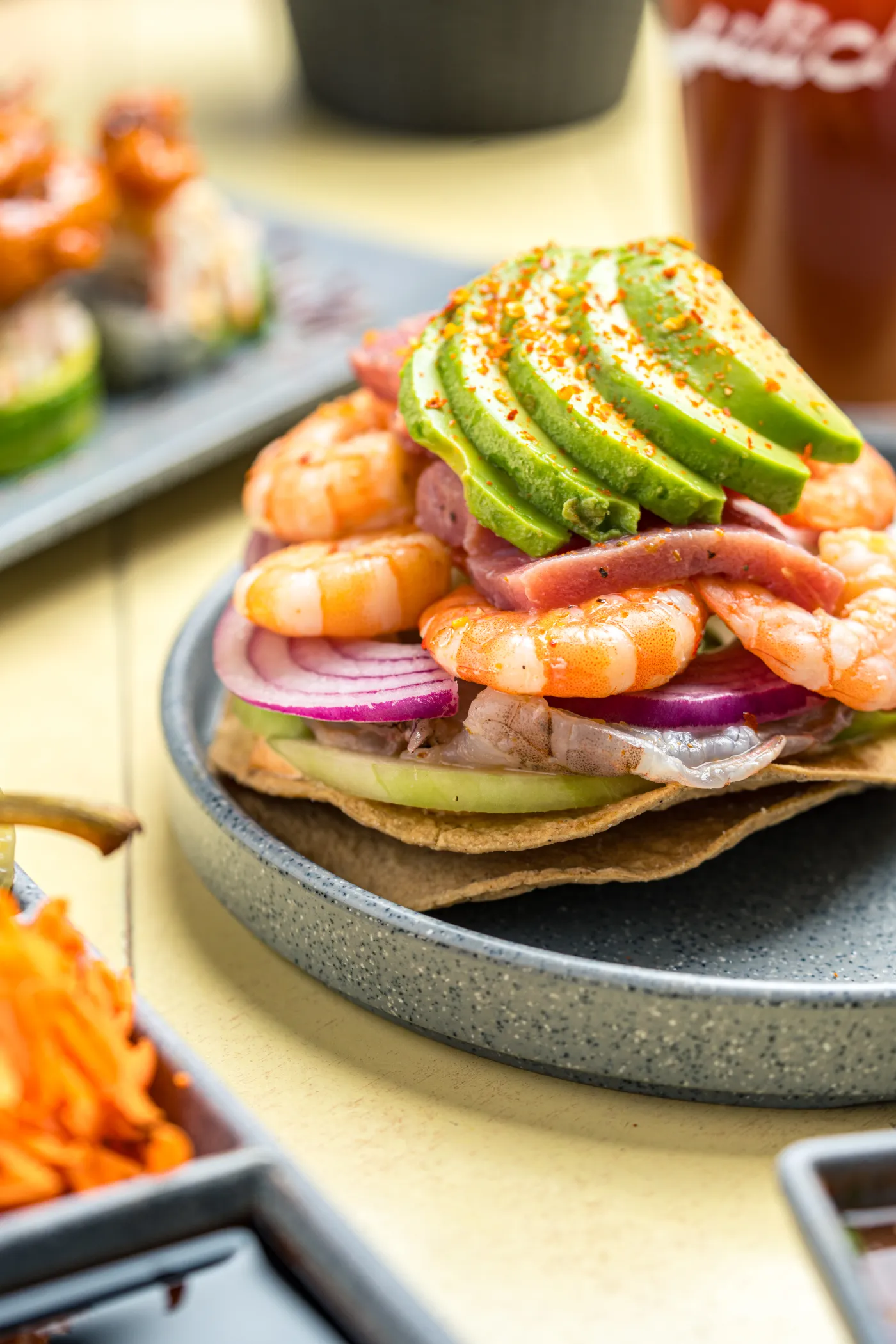 Tostada de camarón con aguacate en rebanadas y cebolla morada