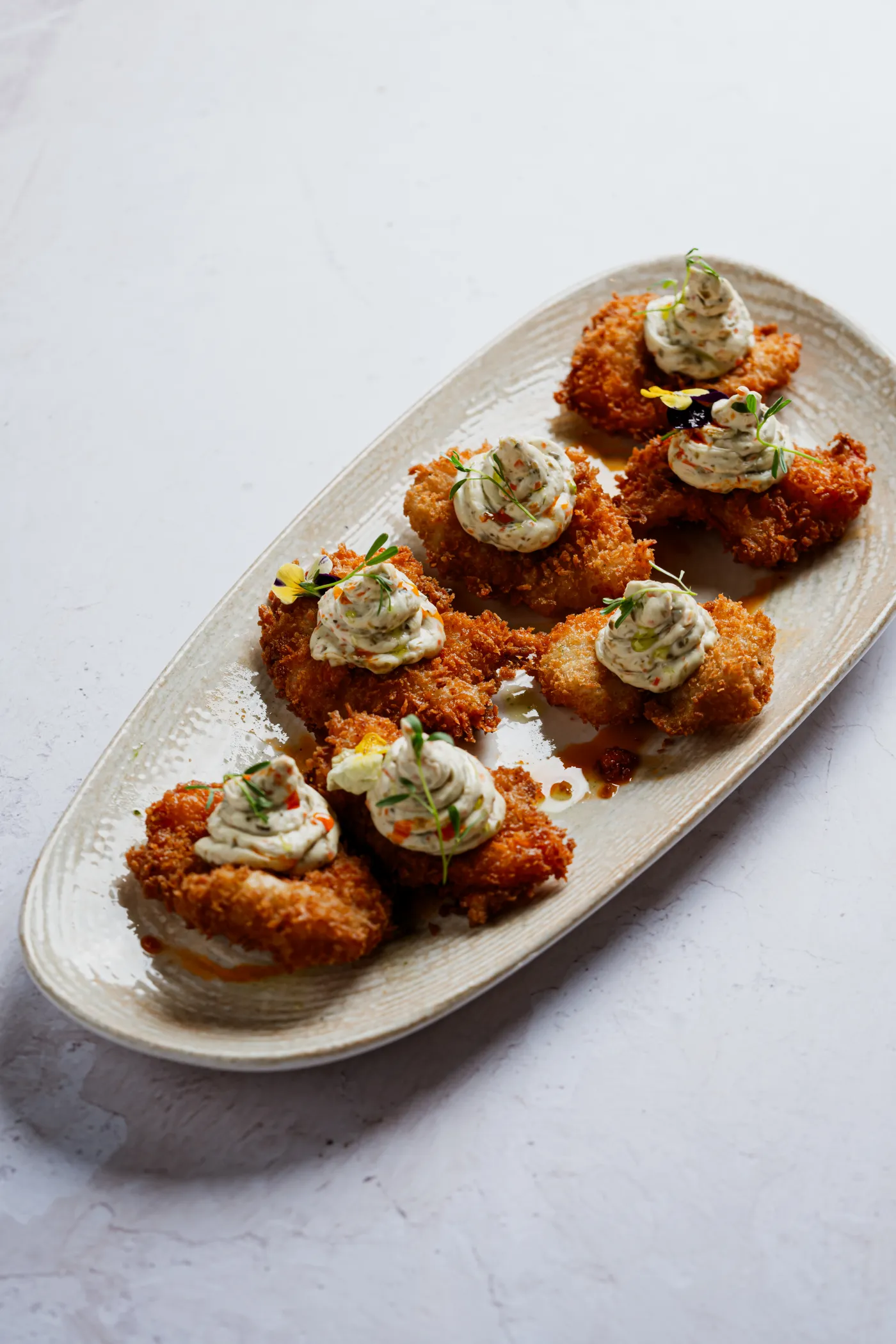 Croquetas empanizadas con crema sobre un plato alargado