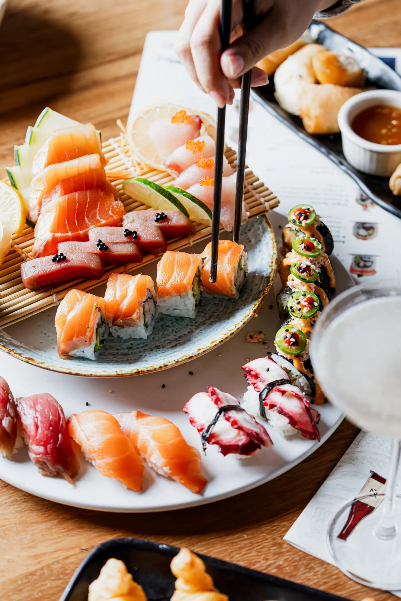 Mesa de sushi y sashimi de salmón, con unos palillos tomando una pieza