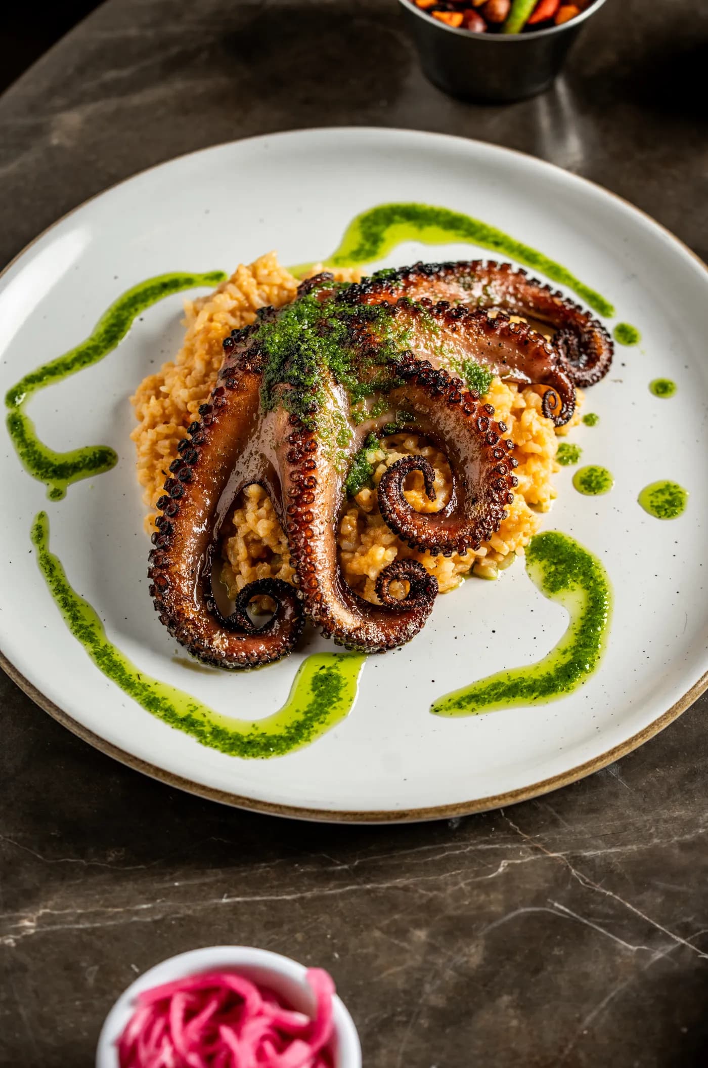 Pulpo a la parrilla sobre arroz con trazos de salsa verde