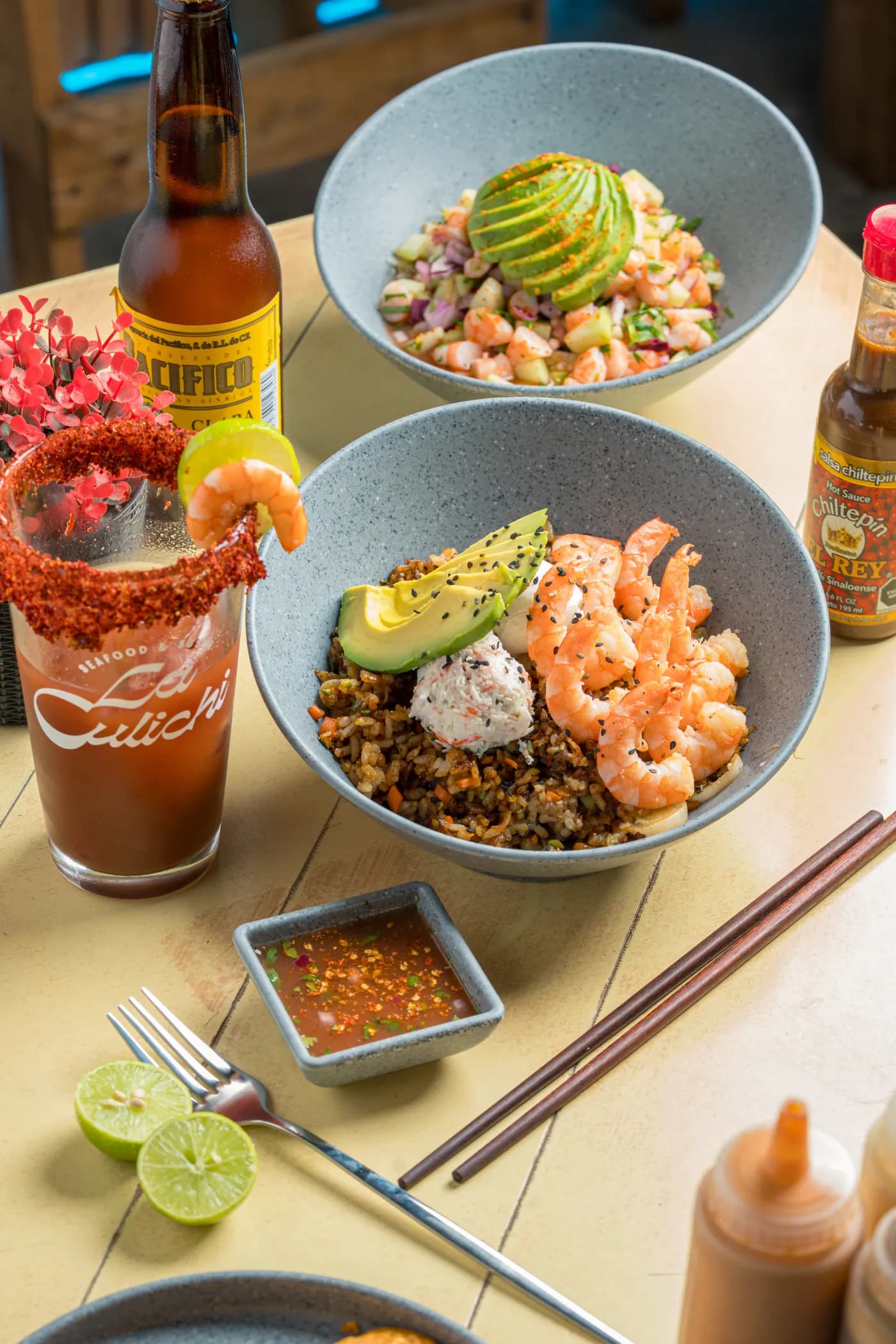 Tazones de camarón con aguacate junto a una michelada y una cerveza