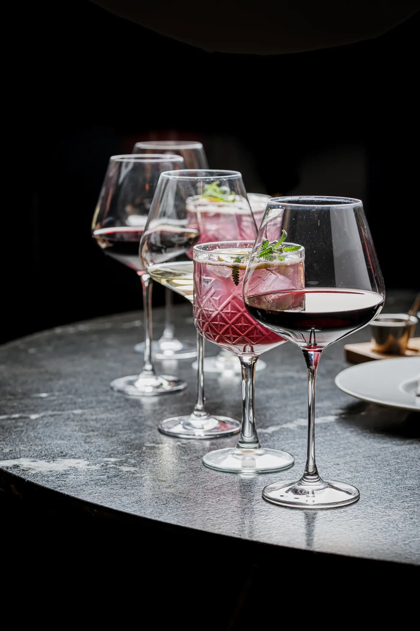 Copas de vino y cocteles sobre una mesa de mármol oscuro