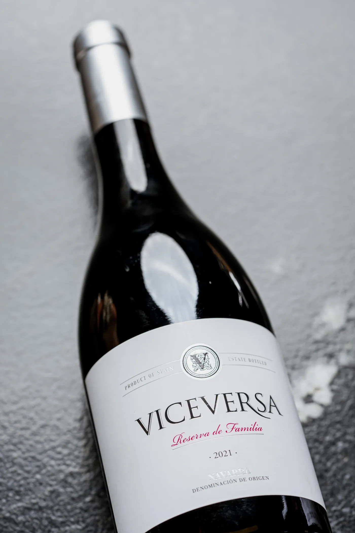 Botella de vino tinto recostada sobre una superficie gris