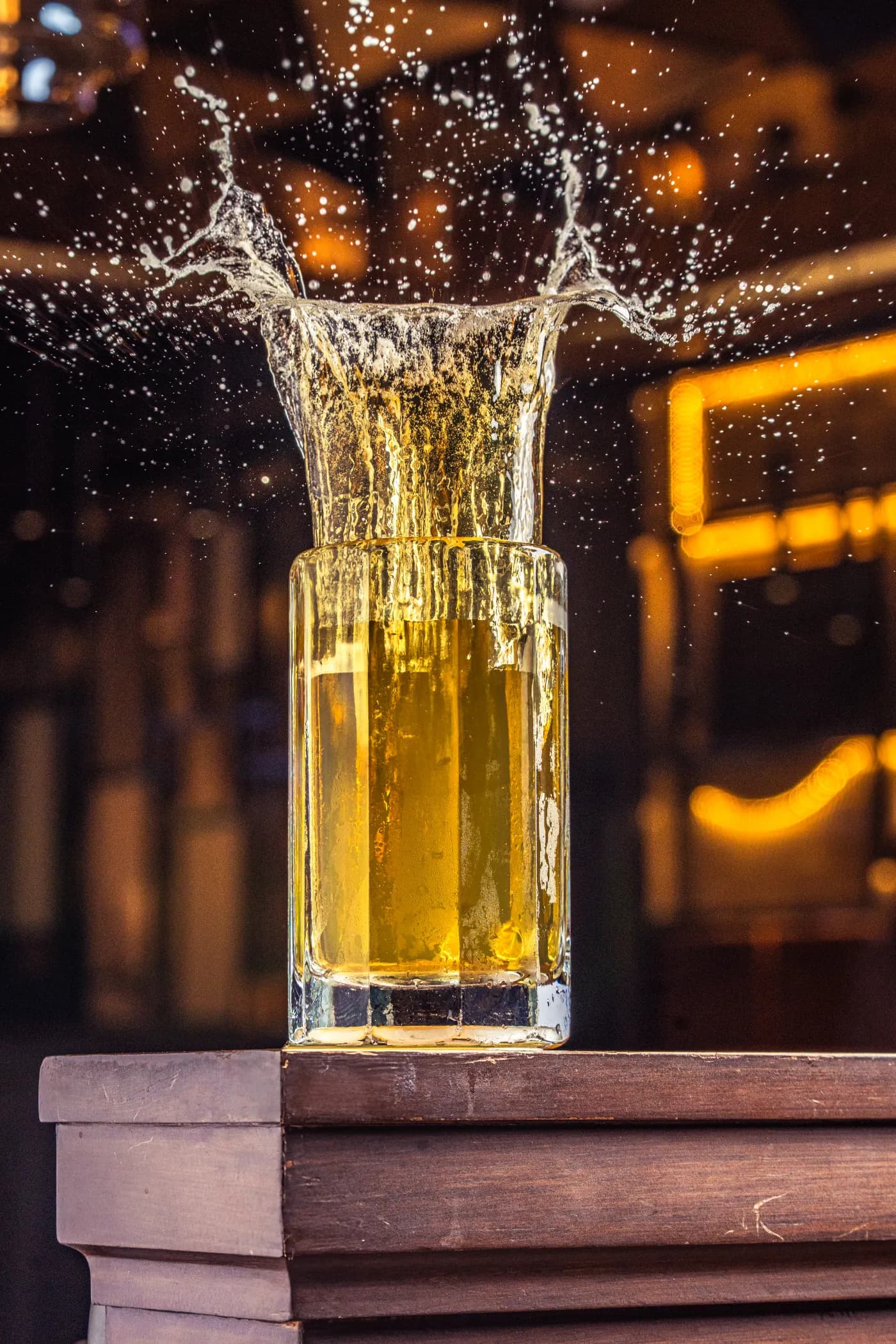 Vaso de cerveza con salpicadura frente a luces cálidas