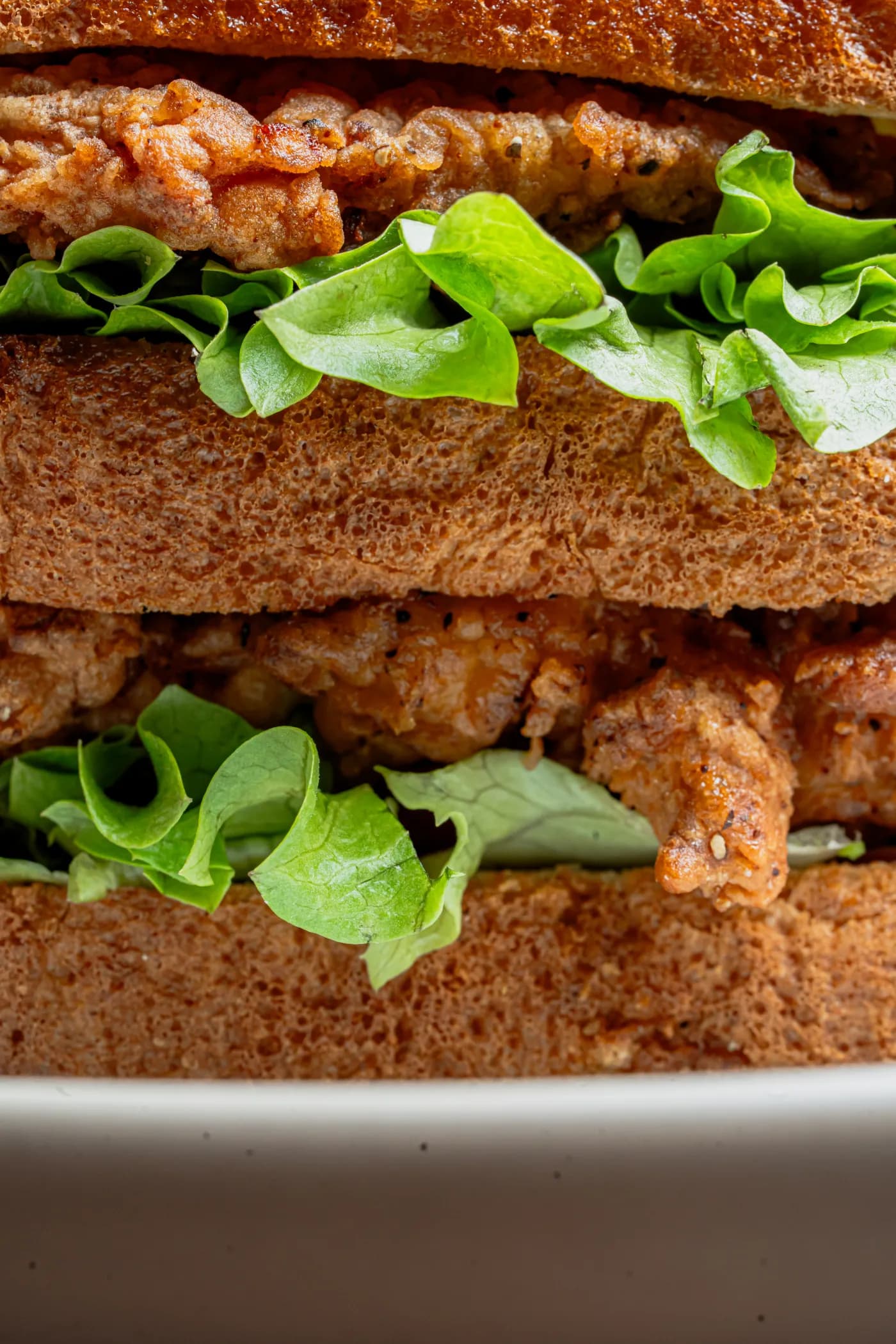 Sándwich de pollo empanizado con lechuga, en acercamiento