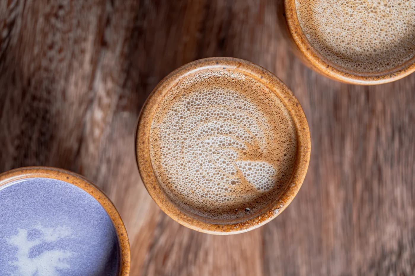 Tazas de barro con café sobre una mesa de madera