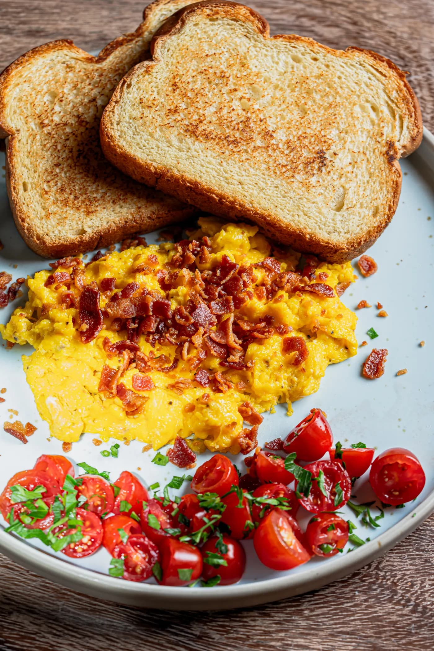 Huevos revueltos con tocino, pan tostado y jitomates cherry